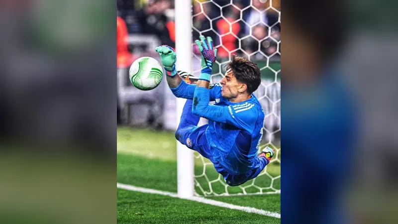 A goalkeeper in blue catching a ball in front of the goal